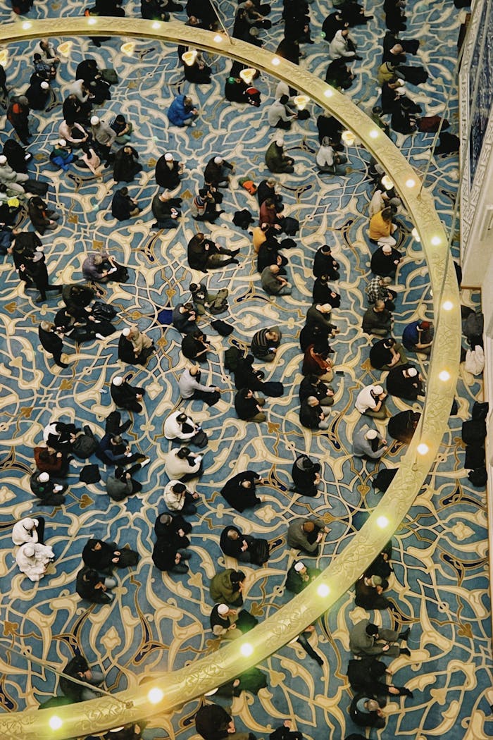 Aerial view of people gathered in a richly decorated interior space with patterned flooring.