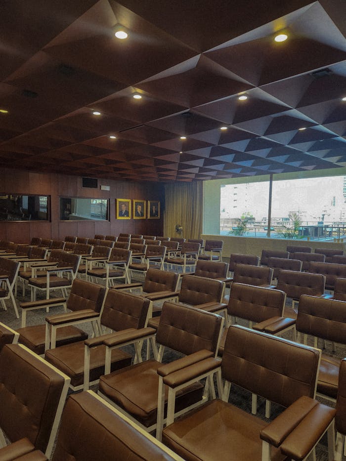 Empty modern conference room with brown cushioned seating and geometric ceiling design.